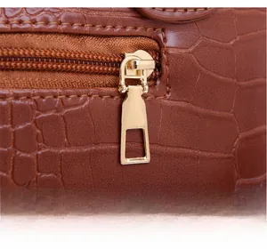 Gros plan sur la fermeture éclair dorée et le cuir à motif crocodile du sac à main