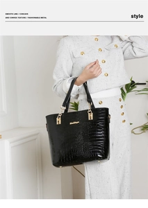 Détail du sac à main noir texture crocodile avec boucles dorées sur tenue en tweed