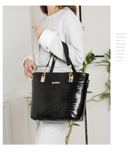 Détail du sac à main noir à texture crocodile avec logo métallique doré élégant