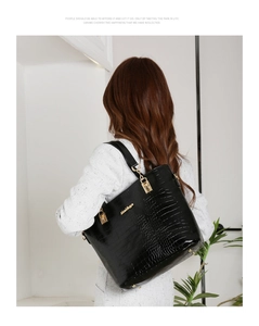 Détail du sac cabas noir à motif crocodile avec logo doré et maillons de chaîne