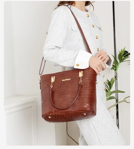 Détails du sac fourre-tout marron foncé à motif crocodile avec logo doré et clous de fond