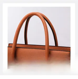 Detail of orange lychee grain leather tote showing double handles and black oil edge finish