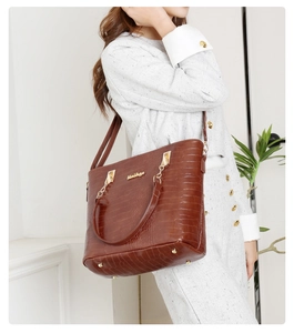 Détail du sac cabas marron à motif crocodile avec garnitures dorées et plaque logo