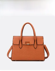 Detail of orange-brown tote bag featuring crocodile embossed texture and golden buckle