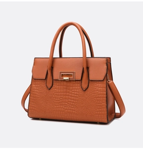Detail of caramel orange tote bag showing contrast lychee and crocodile textures with gold lock