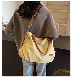 Detailed view of the large canvas tote with brown leather handles and a woven logo patch