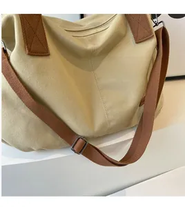 Detail of adjustable brown woven strap and metal buckle on beige canvas tote bag