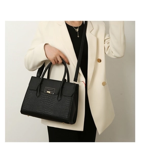 Detail of black faux leather tote with crocodile texture and gold metal square buckle