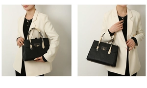 Close-up of black embossed tote bag with gold buckle and snake pattern handle