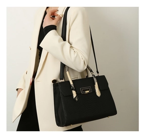 Detail of black snake texture tote bag with gold lock and snakeskin pattern handle
