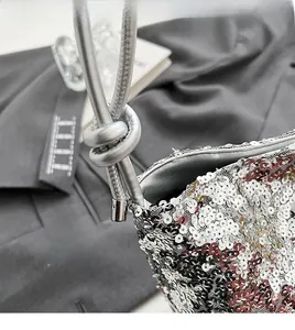 Détail d'un sac sous le bras à paillettes avec bandoulière en corde argentée et nœud