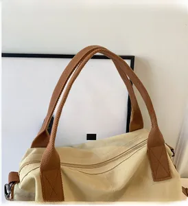 Close-up of beige canvas tote bag showing top zipper and brown woven handles