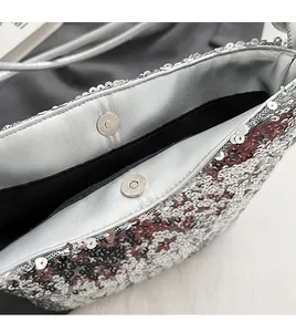 Détail d'un sac à paillettes argentées avec fermoir magnétique et doublure en tissu noir