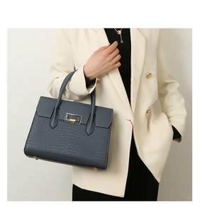 Detail view of a navy blue crocodile pattern tote bag with a golden metal buckle lock