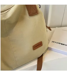 Detailed texture of beige canvas tote bag with brown shoulder strap and brand label