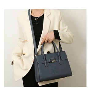 Close-up of blue grey faux crocodile tote bag featuring a metallic lock and shoulder strap