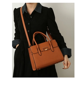 Brown crocodile embossed leather tote bag shown on model featuring gold twist lock hardware