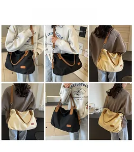 Detail view of large canvas tote bags in black and cream with brown leather trim details
