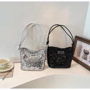 Détails de sacs à main à paillettes argentés et noirs sur un support texturé blanc