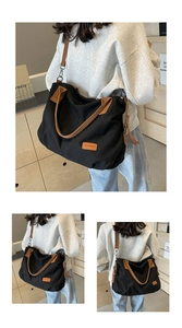 Detail view of large black canvas tote bag with brown straps and leather logo patch