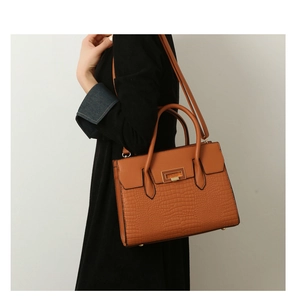 Detail view of brown crocodile embossed leather tote bag with elegant gold hardware