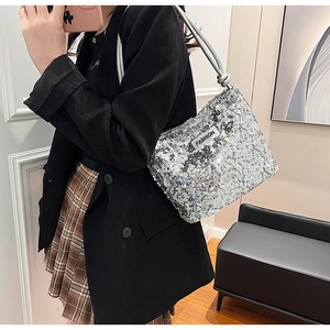Détail d'un sac à bandoulière à paillettes argentées avec étiquette sur un blazer noir
