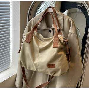Close-up of beige canvas tote bag with brown straps hanging on a classic trench coat