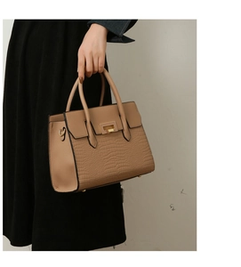 Detail view of khaki embossed crocodile pattern tote bag with gold metal clasp