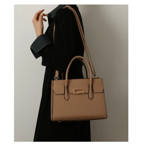 Detailed side view of camel crocodile embossed tote bag with dual handles and gold buckle