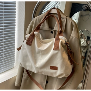 Detail of canvas tote bag showing brown webbing handle and metal strap buckle
