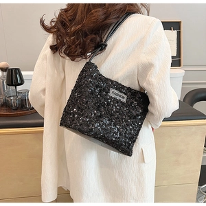 Détail du sac à bandoulière à paillettes noires avec écusson FASHION sur un mannequin