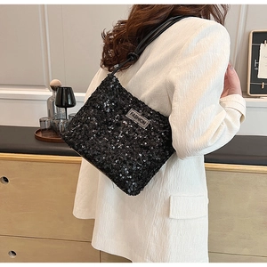 Détail de paillettes noires scintillantes et du logo métallique argenté sur le sac à bandoulière