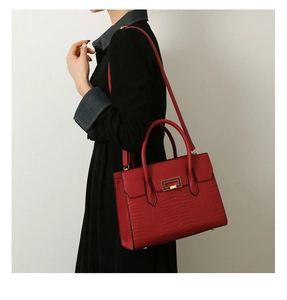Detail of red embossed crocodile pattern tote bag with gold metal buckle and studs
