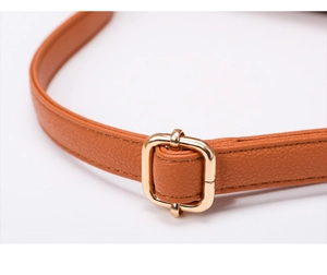 Close-up of brown leather shoulder strap with gold metal buckle and pebbled texture