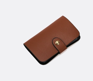Detailed macro view of brown lychee grain leather wallet with a golden snap button