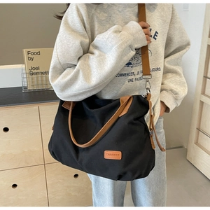 Detailed view of black canvas tote bag with brown handles and TAIMEIBAG logo label