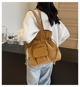 Brown corduroy drawstring shoulder bag with a front flap pocket shown on model