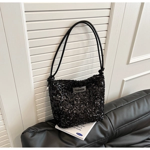 Détail d'un sac à main noir à paillettes avec étiquette FASHION sur cuir noir