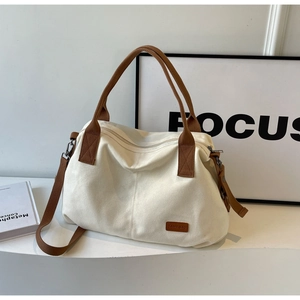 Detail of minimalist cream canvas tote bag with brown straps and zipper closure