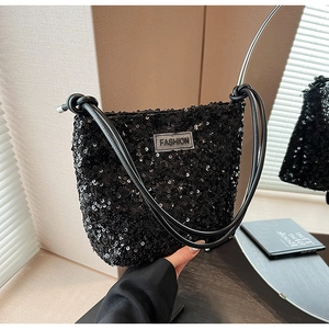 Détail d'un sac à bandoulière noir à paillettes avec une étiquette logo mode à l'avant