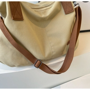 Close-up of beige canvas tote bag with brown fabric strap and zip closure detail