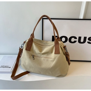 Close-up of canvas tote bag with brown straps and functional metal zipper pocket