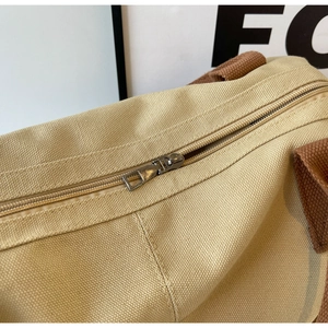 Detailed macro view of the metal zipper and woven handle on a beige canvas tote bag