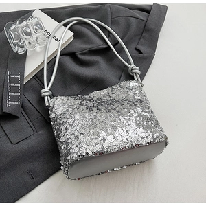 Gros plan d'un sac à bandoulière en paillettes argentées avec poignée à nœud sur tissu