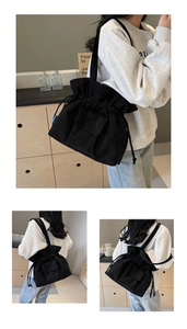 Detail of black corduroy shoulder bag showing drawstring closure and front flap pocket