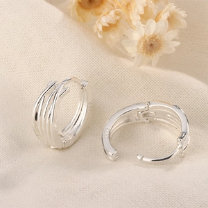 Macro view of multi-layer silver hoop earrings featuring the S925 hallmark on metal