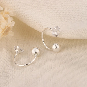 Minimalist silver C-shaped zircon earrings with polished metal finish on textured fabric