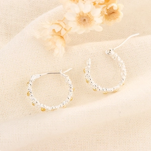 Boucles d'oreilles créoles marguerites argentées à pois dorés sur fond beige