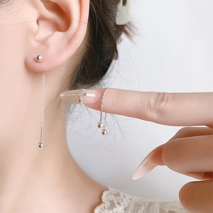 Detail showing minimalist silver bead threader earrings on ear with long flexible chain