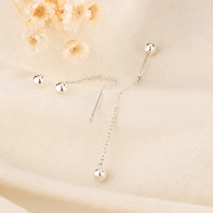 Detailed view of minimalist S925 sterling silver bead drop earring on soft textured fabric